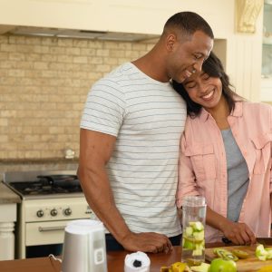 Happy young african american couple preparing food together in kitchen at home